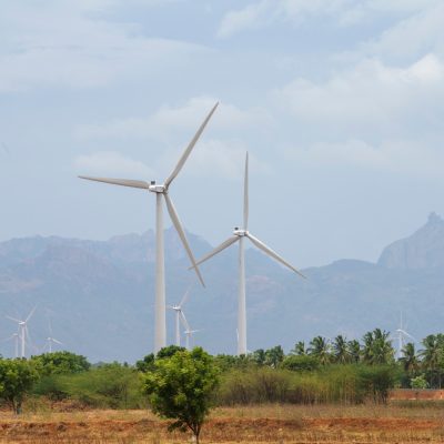 Windmill - Wind turbine below the mountain on the agriculture land. Alternate energy source generator with environment friendly. Wind turbines for ecological power supply